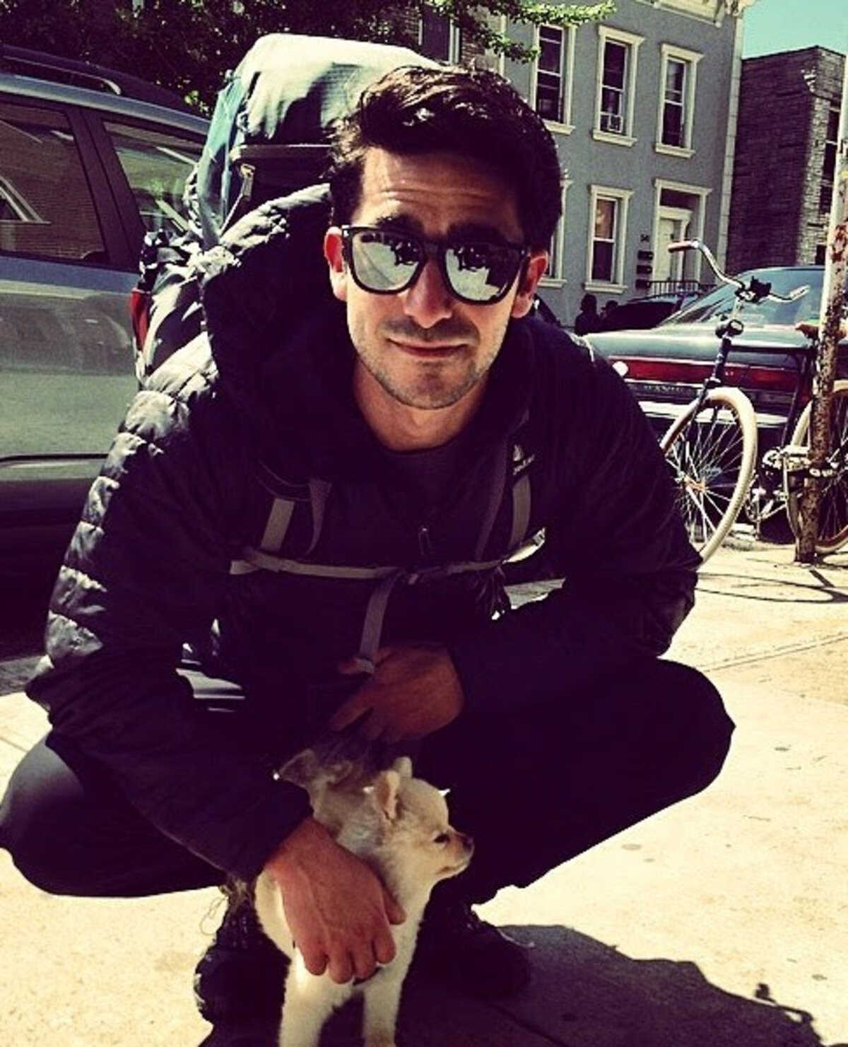 Peter in Brooklyn, clean-shaven with a backpack, holding a small dog the day he left for India.